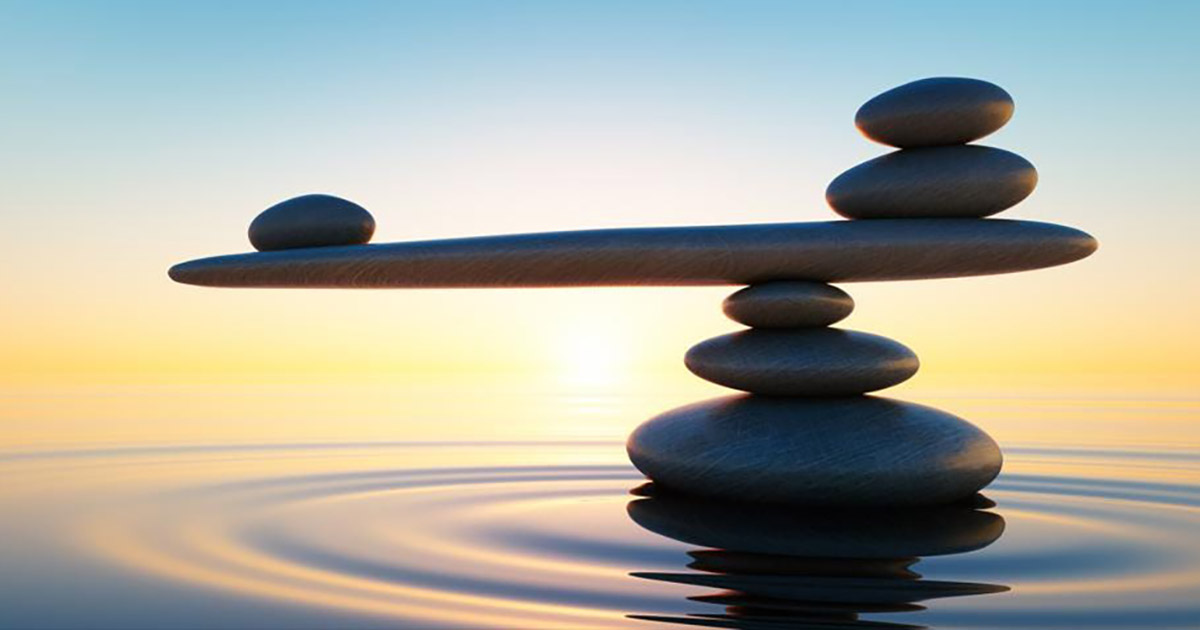 Stack of stones in calm water with seesaw in the evening sun